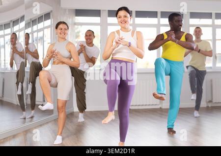 Young Asian woman practicing vigorous zumba with group Stock Photo