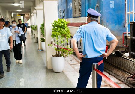 Long Bien Railway Station,Hanoi Vietnam-June 11 2025: A station guard looks on as disembarking customers leave the railway platform. Stock Photo