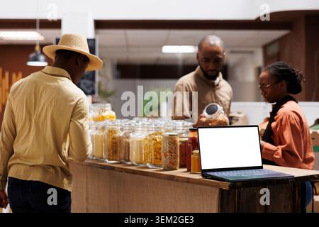 In an eco friendly shop, the selective focus is on a minicomputer presenting an isolated copyspace template for adverts. A digital laptop at a modern grocery store displays a blank white screen. Stock Photo