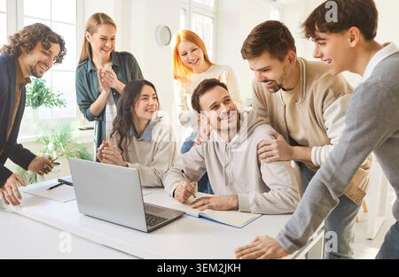 Diverse students collaborating on group project with laptop in bright study space Stock Photo