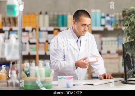 Male pharmacist checking information about medicine on computer Stock Photo