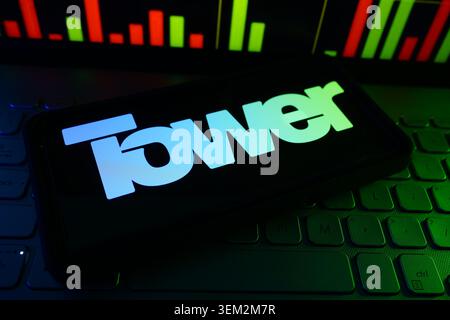 Tower Semiconductor Specialty Foundry Company Logo On A Screen With A Live Stock Chart In The Background Stock Photo