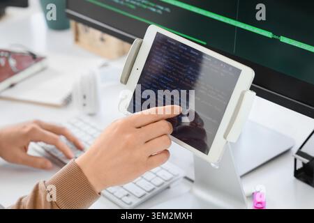 Female programmer's hands testing code on tablet computer in office, closeup Stock Photo