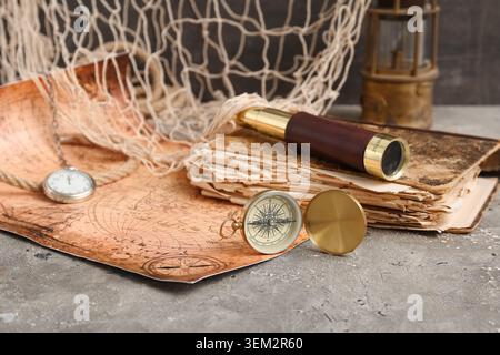 Golden compass, world map, net, spyglass and old book on grey grunge background Stock Photo