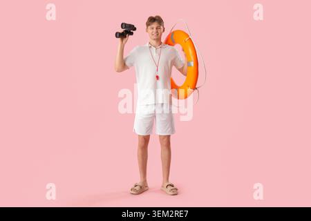 Male lifeguard with ring buoy and binoculars on pink background Stock Photo