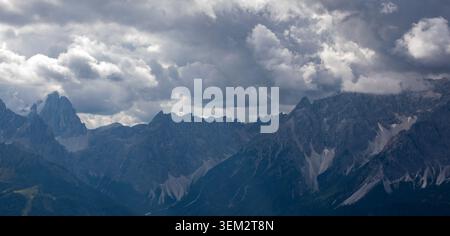 View of the jagged peaks of the Dolomites mountain range under a dramatic overcast sky with heavy grey clouds Rocca Pietore, Veneto, Italy. Stock Photo