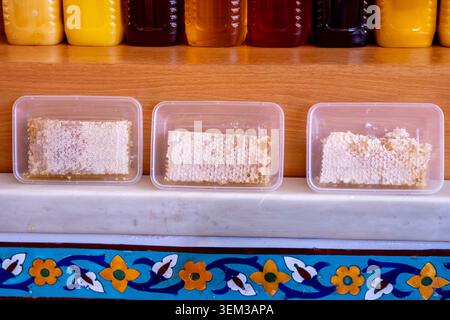 Honeycomb containers on shelves, against a backdrop of jars of various honeys. Concept: bees give us health Stock Photo