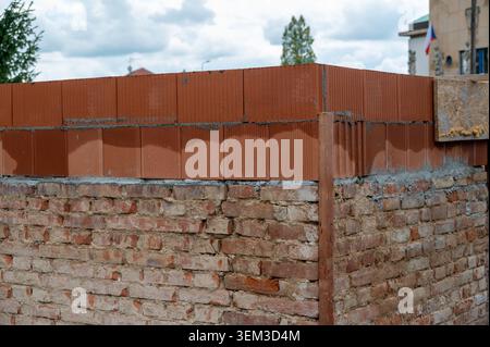 Construction of a house showing contrast between old fired brick foundation and a newly built upper floor from modern brick blocks. Blend of tradition Stock Photo