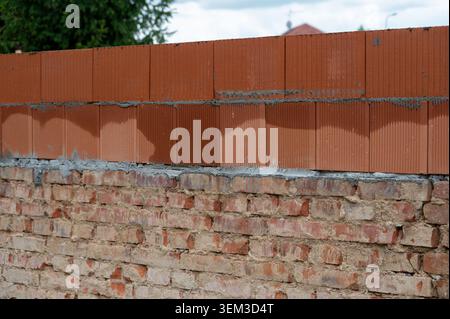 Construction of a house showing contrast between old fired brick foundation and a newly built upper floor from modern brick blocks. Blend of tradition Stock Photo