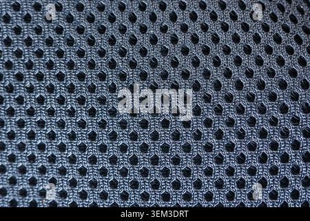 Calm macro texture of dark blue mesh fabric background displaying uniform geometric pattern with small breathable hole in synthetic material for moder Stock Photo
