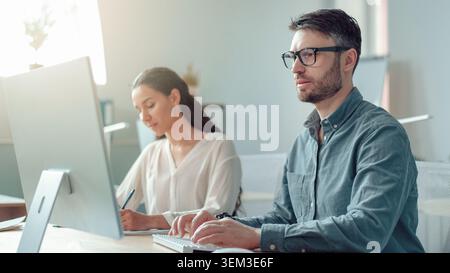 Focused Male And Female Professionals Working Together In Modern Office, Business Concept Stock Photo