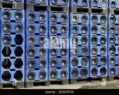 View of stacked blue plastic crates filled with large water bottles on wooden pallets under bright daylight Sariyer, Istanbul, Turkiye. Stock Photo