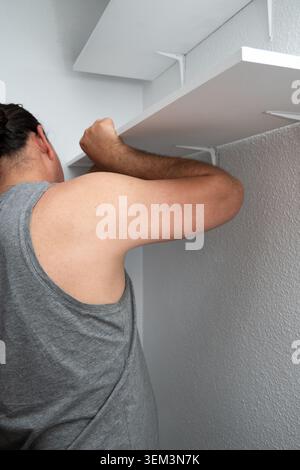 Man installing new shelf bracket for home renovation project inside a closet Stock Photo
