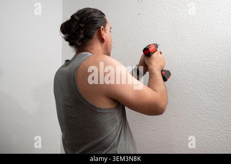 Man using power drill, making hole in wall for home improvement Stock Photo