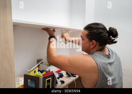 Man installing a new shelf, performing home renovation and hands-on DIY work Stock Photo