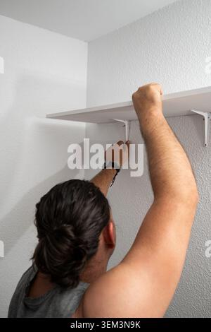 Man installing shelf brackets during home improvement project Stock Photo