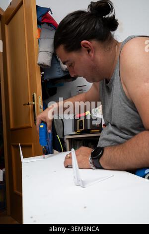 Man drilling screw into shelf bracket for home improvement project Stock Photo