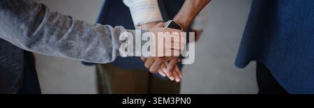 Diverse Adults Joining Hands While Volunteering in Aid Center Stock Photo