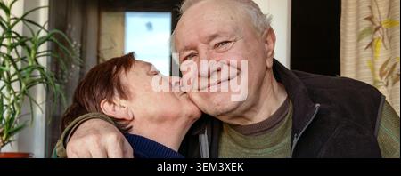 Heartwarming portrait of a happy elderly couple sharing affection. Senior woman lovingly kisses her beloved husband on the cheek, expressing love, car Stock Photo