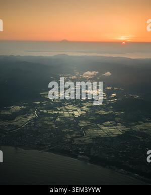 Aerial view of a rural landscape at sunset, featuring rolling fields ...