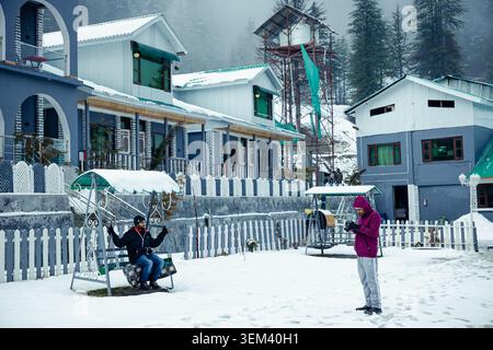 Tourists relaxing and taking photos at a snowy mountain resort during a cold winter day in Kashmir, India. Stock Photo