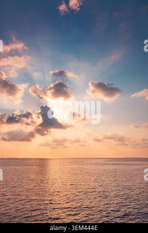 Dramatic sunbeams breaking clouds calm ocean twilight sky light rays sea reflection horizon. Summer evening seascape landscape. Wellness spirituality Stock Photo