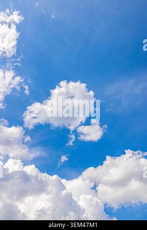 Blue sky with fluffy white clouds on a bright sunny summer day. Clear cloudscape sunshine. Sky clouds nature background heaven copy space peaceful Stock Photo