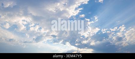 Heavenly sun rays breaking through dramatic clouds in wide panoramic sky. Sunbeams light natural cloudscape. Spiritual hope background copy space Stock Photo