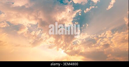 Golden sunbeams glowing clouds warm sunset light breaking through sky heaven radiant rays. Summer cloudscape nature landscape. Wall art wallpaper art Stock Photo