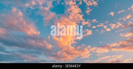 Pastel pink orange sunset clouds drifting across soft blue evening sky. Dramatic cloudscape natural backdrop. Peaceful heaven background copy space Stock Photo