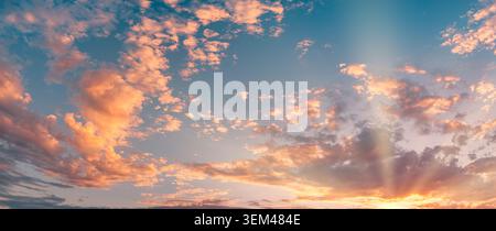 Gorgeous panoramic sunset sky over glowing orange clouds sunbeams blue horizon. Summer evening cloudscape landscape. Wall art backdrop design scenic Stock Photo