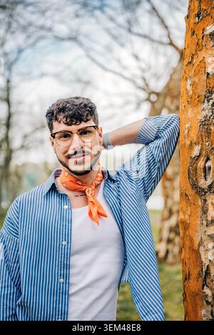 Young man smiling wearing glasses against tree Stock Photo
