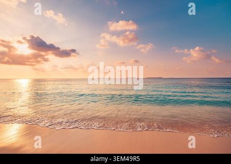 Soft pastel sunset over calm beach, gentle waves washing smooth sand, sun glow reflecting on tranquil sea surface, peaceful evening shore scenic Stock Photo