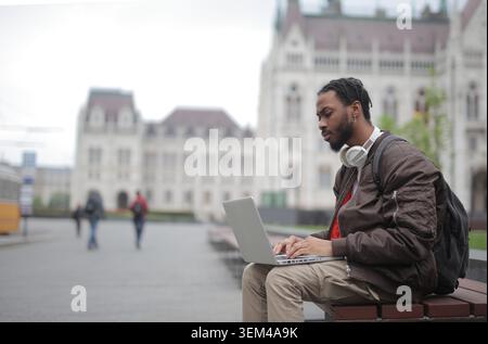 Focused young man works on laptop in a city square Stock Photo