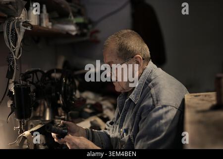 Elderly artisan carefully working in his shop Stock Photo