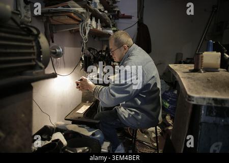 Elderly Asian artisan repairing a shoe in his workshop Stock Photo