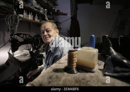 Elderly shoemaker pauses for a portrait in his workshop Stock Photo