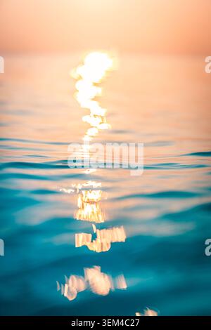 Sun trail shimmer rippled sea surface dusk. Vertical minimalist ocean reflection. Golden light stretching horizon, meditative seascape Stock Photo