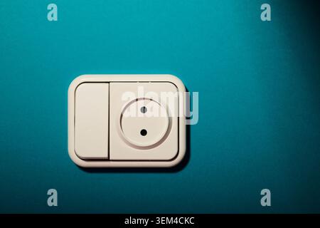 Close-up of a white switch socket, joined into a single device, on the green wall of a house. Stock Photo