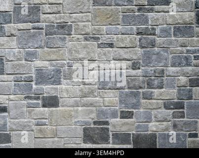 Horizontal close up of a rock wall and mortar surface with rectangular and square gray stone blocks in varied sizes Stock Photo