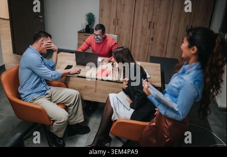 Business teammates laughing and chatting during an informal meeting in a modern office Stock Photo