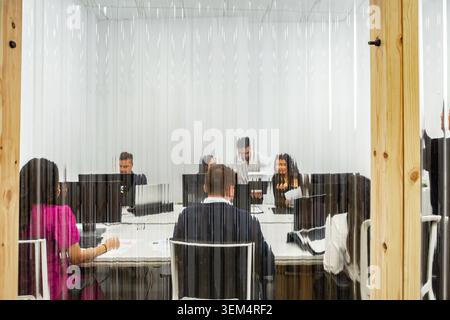 A group of professionals engages in a collaborative session inside a coworking space. The meeting takes place in a flexible workspace designed for tea Stock Photo