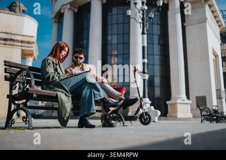 Two colleagues sitting on a bench discussing notes outside a neoclassical office building Stock Photo