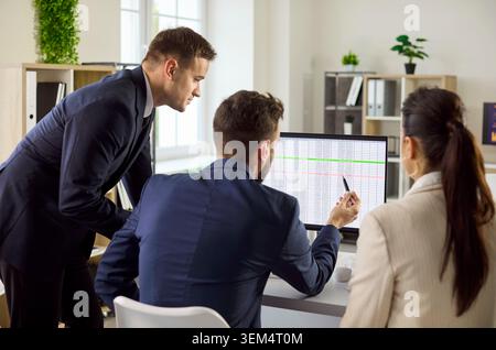 Managers review project data on computer, planning tasks and strategy in office Stock Photo
