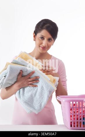Young woman holding a pile of towels Stock Photo - Alamy
