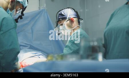 Clinic group of three doctors surgeons in innovative hospital performing clinical difficulty operation neurosurgery treatment working therapy Stock Photo