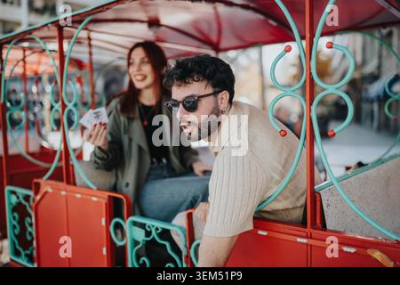 Young enjoying a colorful amusement ride together on a sunny urban outing Stock Photo
