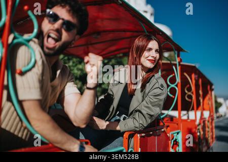 Young enjoying a sunny city sightseeing ride in a colorful open-air tourist train Stock Photo