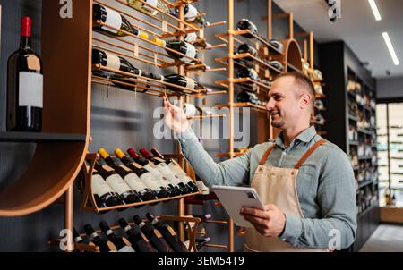 Sommelier checking wine inventory in a modern shop using a digital tablet Stock Photo