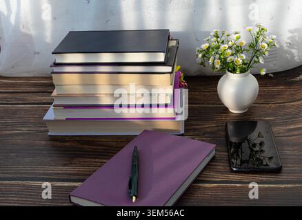 Notebook with Stack of Books and Smartphone on Wooden Study Desk Stock Photo